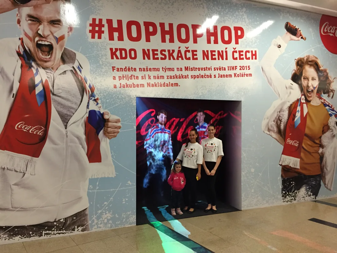 Návštěvnice u mlžné instalace Coca-Cola s hokejovou tematikou.