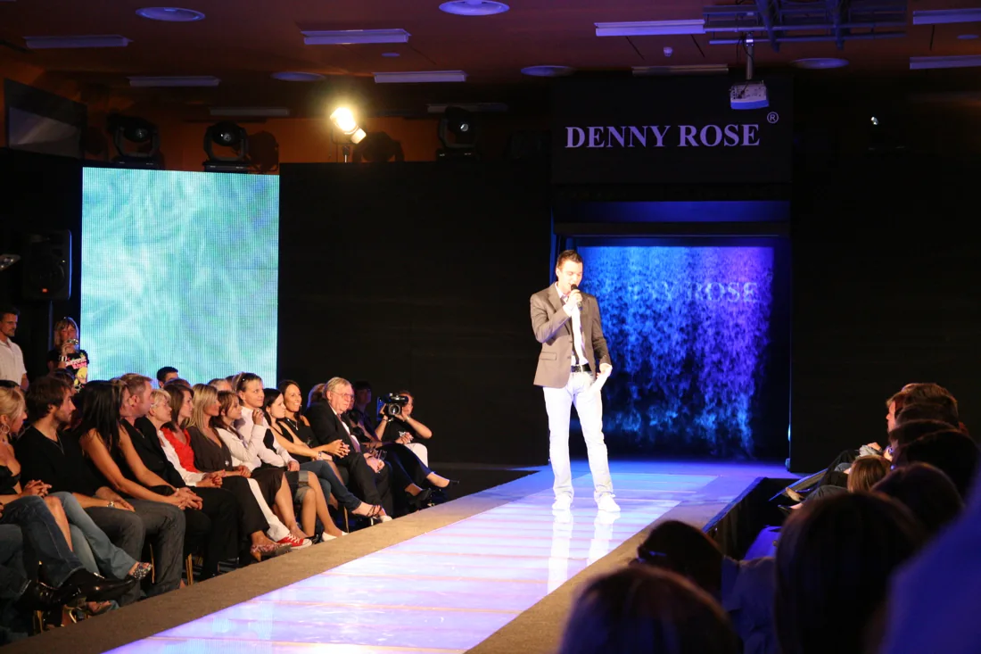 Přehlídkové molo Denny Rose s mlžnou projekcí za moderátorem.